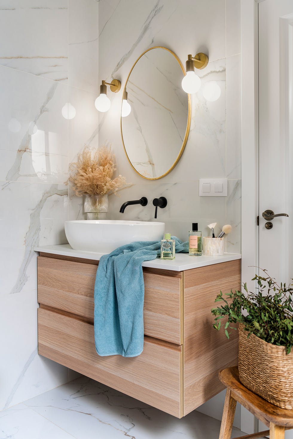 lavabo con mueble flotante de madera y espejo redondo con marco dorado