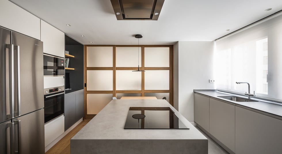 cocina abierta de diseño moderno con isla central efecto cemento y puerta corredera
