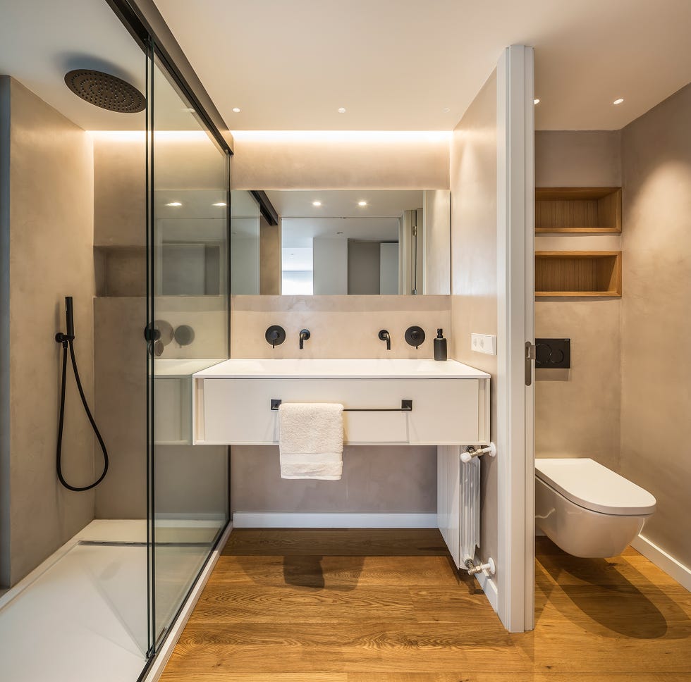 baño con ducha de obra, mueble de lavabo flotante y suelo de madera