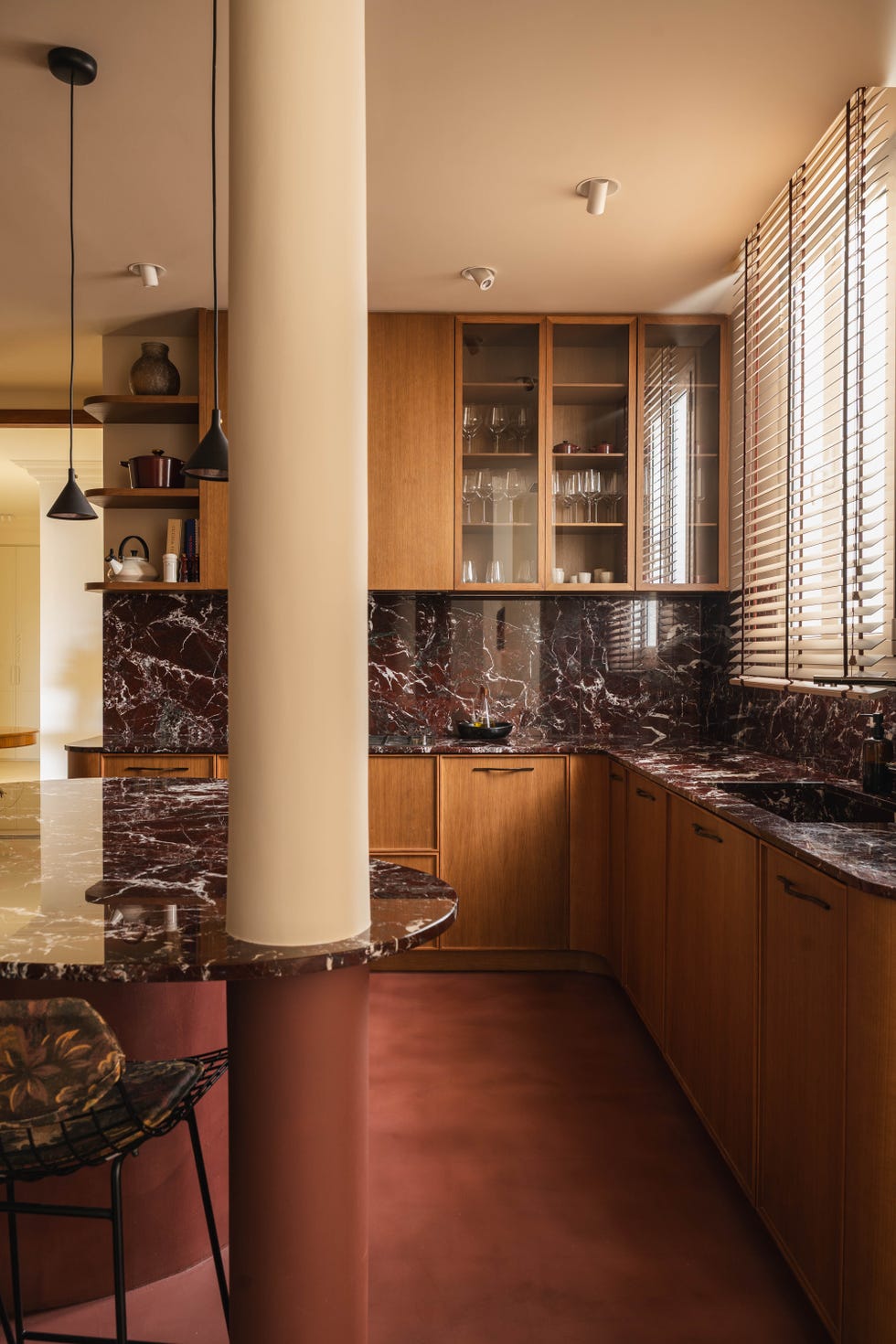 cocina con isla curva y encimera de piedra burdeos