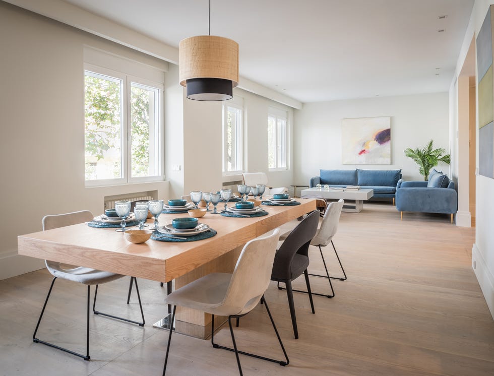 salón comedor con mesa de madera alargada, sillas y sofás tapizados en terciopelo