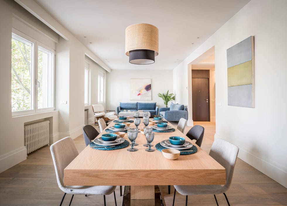 salón comedor con mesa de madera alargada, sillas y sofás tapizados en terciopelo