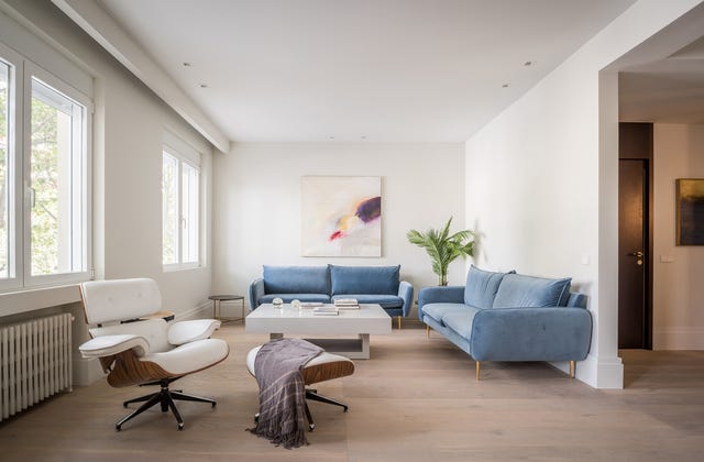 salón de diseño contemporáneo con dos sofás de terciopelo azul y una butaca con reposapiés en blanco