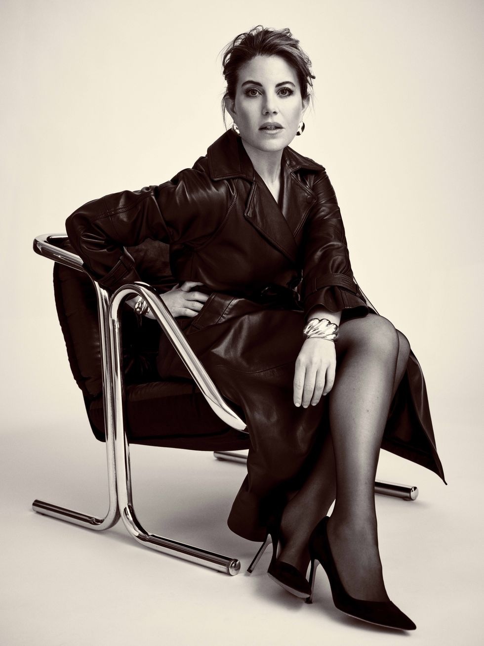 a brunette woman sitting in a modernist chair
