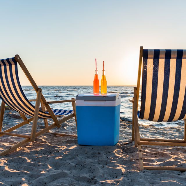 refreshing beverages on cooler and chaise lounges on sandy beach at sunset