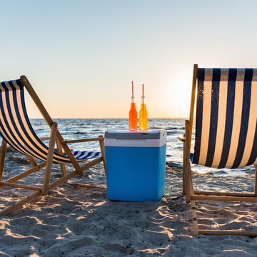 refreshing beverages on cooler and chaise lounges on sandy beach at sunset