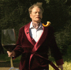 un lord inglés camina por el campo fumando en pipa y con una copa de vino gigante en la mano