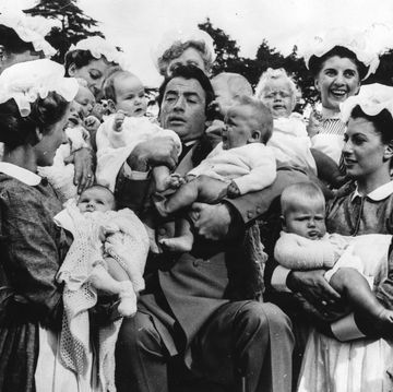 el actor gregory peck sostiene a varios bebés en brazos junto a un grupo de enfermeras en la película 'the million pound note'