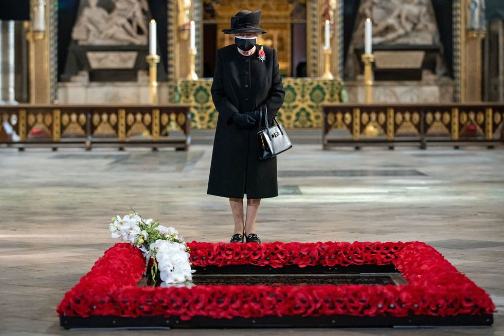 britains queen elizabeth ii looks on after her equerry, lieutenant colonel nana kofi twumasi ankrah placed a bouquet of flowers at the grave of the unknown warrior to mark the centenary of the burial of the unknown warrior ahead of remembrance sunday at westminster abbey in london on november 4, 2020   in the small private ceremony, the queen honoured the unknown warrior and the royal familys own associations with the first world war and the grave at westminster abbey as part of the ceremony, a bouquet of flowers featuring orchids and myrtle   based on her majestys own wedding bouquet from 1947   was placed on the grave of the unknown warrior in an act of remembrance the gesture reflected the custom of royal bridal bouquets being placed on the grave photo by aaron chown  pool  afp photo by aaron chownpoolafp via getty images