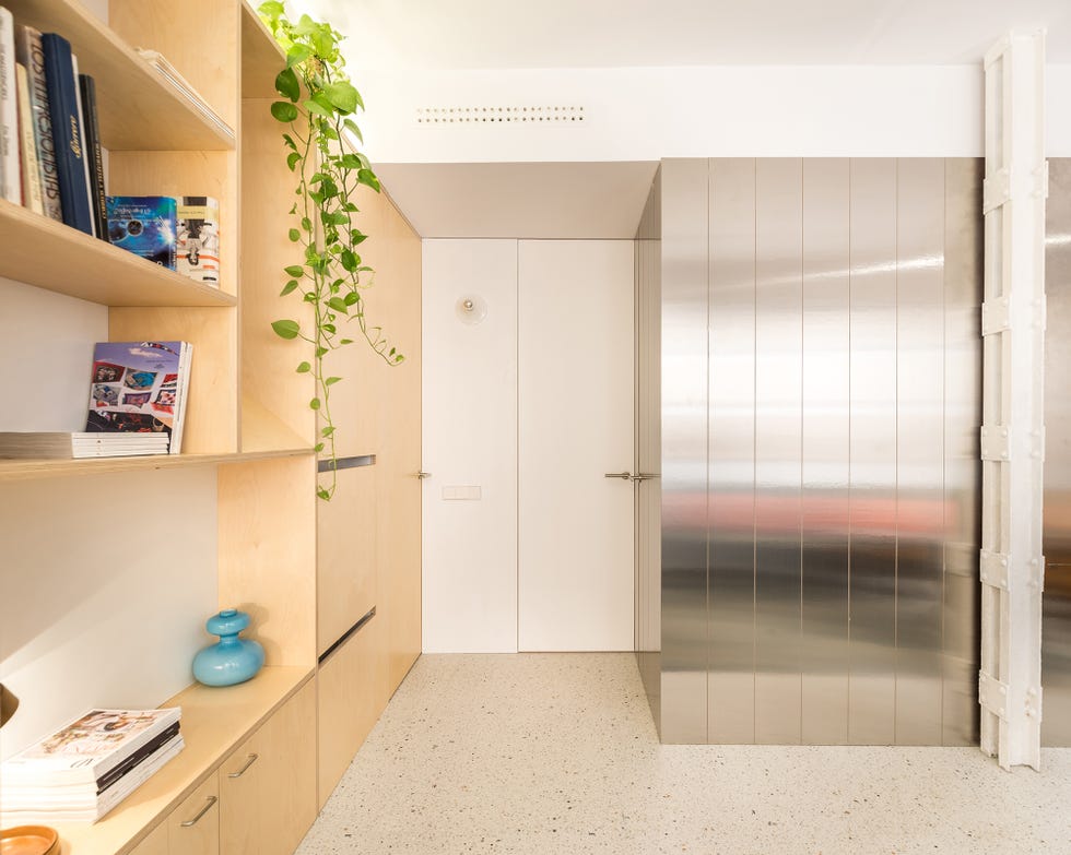 estantería de abedul y volumen de acero inoxidable en el salón