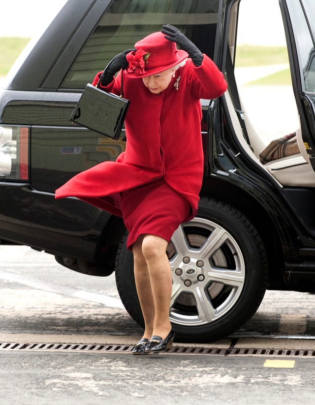 la reina isabel ii en una divertida foto luchando contra el aire