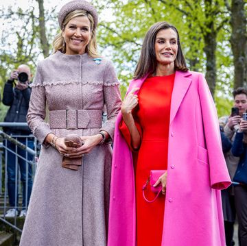 la reina letizia con abrigo rosa y vestido naranja