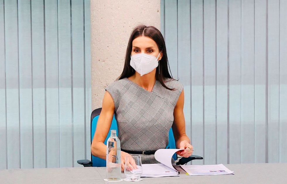 la reina letizia sentada en una silla con unos documentos