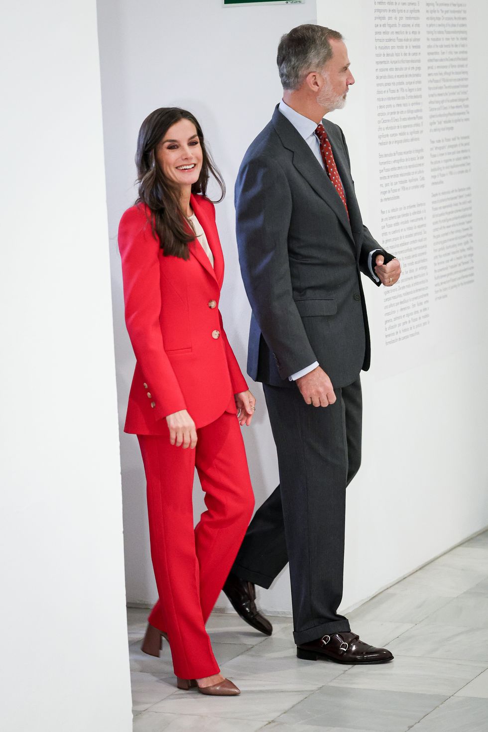 la reina letizia y el rey felipe con conjuntos rojos en la exposición de picasso