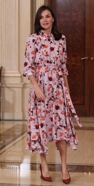 la reina, con un vestido rosa con estampado de flores, en una audiencia