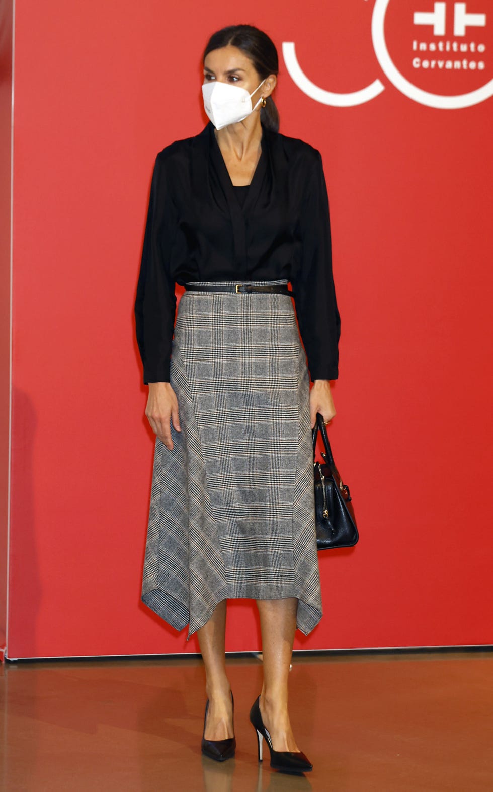 doña letizia en san sebastián con una camisa negra cruzada y falda de cuadros