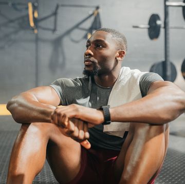 relax, thinking and black man in training gym resting his body after weightlifting workout muscular, healthy and strong fitness person on exercise break thoughtful while relaxing on floor