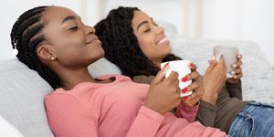 relaxed african ladies drinking tea, talking while resting on couch