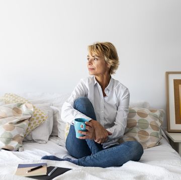 relaxed mature woman sitting on bed at home