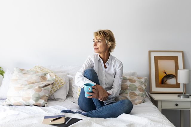 relaxed mature woman sitting on bed at home