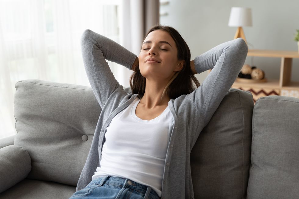 relaxed serene young woman lounge on comfortable sofa at home