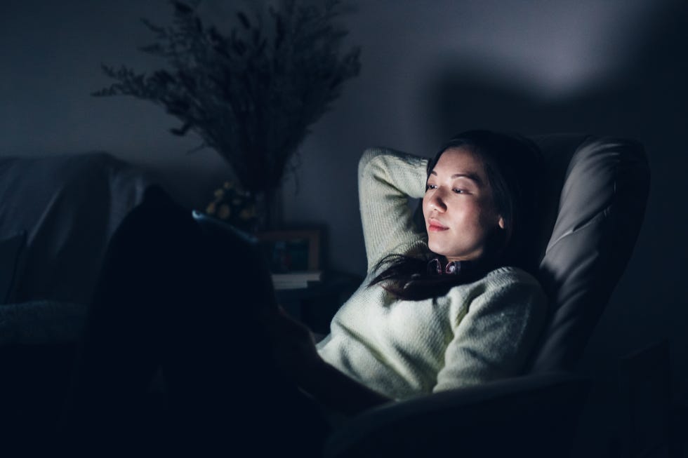 relaxed woman reading on digital tablet at night