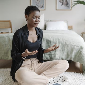 relaxed woman sitting on the floor practicing meditation after reading book