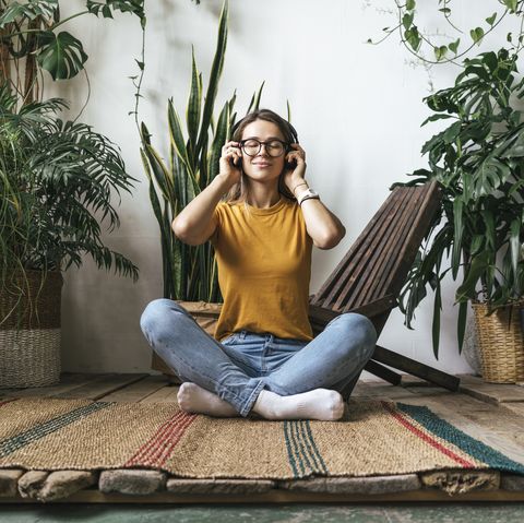 relaxed young woman sitting on the floor at home listening to music