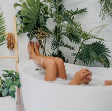 vrouw ligt in bad met planten om haar heen