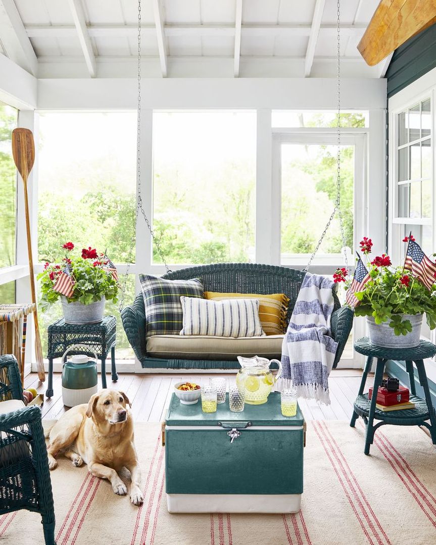 a screened porch with green wicker furniture