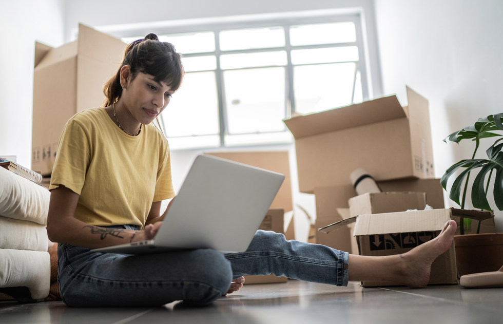 a person sitting on the floor with a laptop as they've moved flat