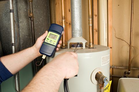 repairman checks carbon monoxide level on gas water heater exhaust