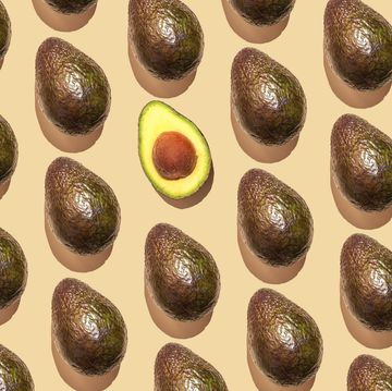 repeated avocado and one halved avocado fruit on the beige background