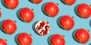 repeated pomegranates and one half sliced pomegranate on the blue background