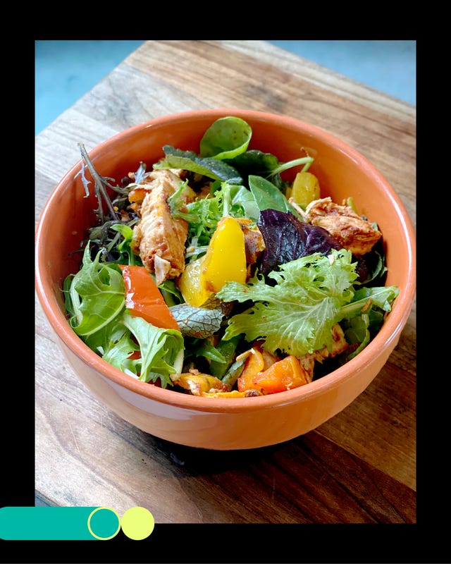 a colorful salad featuring mixed greens grilled chicken and assorted vegetables in a round bowl a colorful salad featuring mixed greens grilled chicken and assorted vegetables in a round bowl