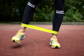 person working out with yellow resistance band around ankles on track