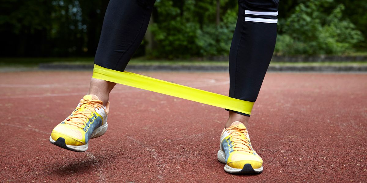 person working out with yellow resistance band around ankles on track