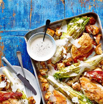 a tray with roast chicken, lettuce, croutons, pancetta, cheese and a bowl of dressing