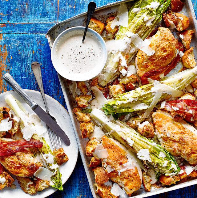 a tray with roast chicken, lettuce, croutons, pancetta, cheese and a bowl of dressing