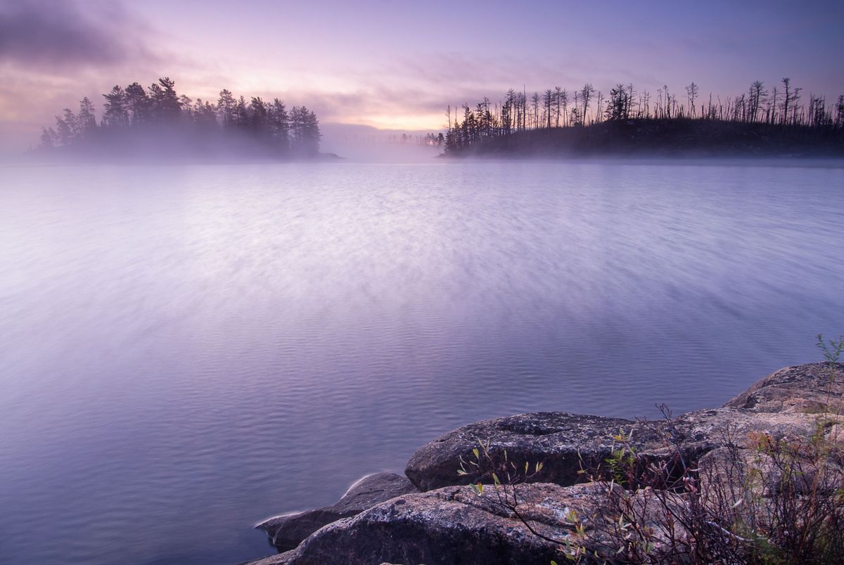 Bij zonsopgang hangen paarsroze mistflarden boven Saganaga Lake in Minnesota een van de vele langgerekte meren die deel uitmaken van de Border Route een historisch belangrijke indiaanse handelsroute die nu geliefd is bij avontuurlijke hikers en kanovaarders