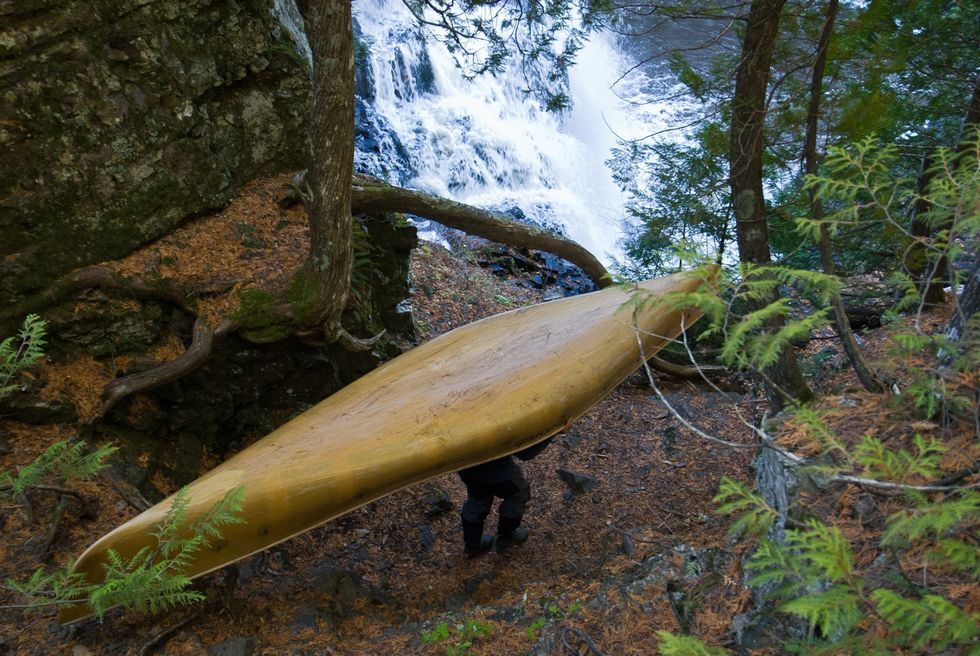Dave Freeman steekt het gedeelte van de Pigeon River met daarin de Partridge Falls af door zijn kano over een bospad stroomafwaarts te dragen
