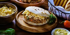 venezuelan traditional food arepa pelua or white corn arepa with shredded cheese and meat ingredients on a table in a rustic kitchen corn flour, cheese, corn cobs, butter, water and salt arepas, or corn bread, is a main meal in the venezuelan culture and cuisine