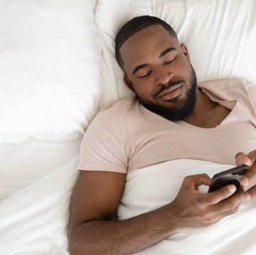 rested african american man waking up at comfortable bed