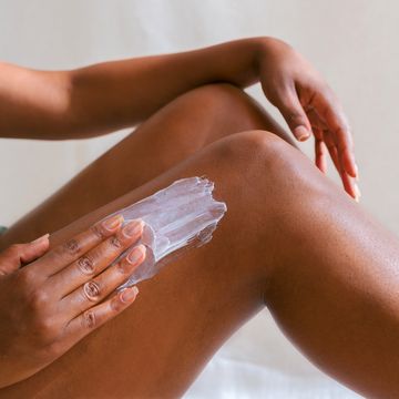 a close up of hands rubbing lotion on leg