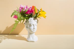 retro head sculpture with flowers on beige background