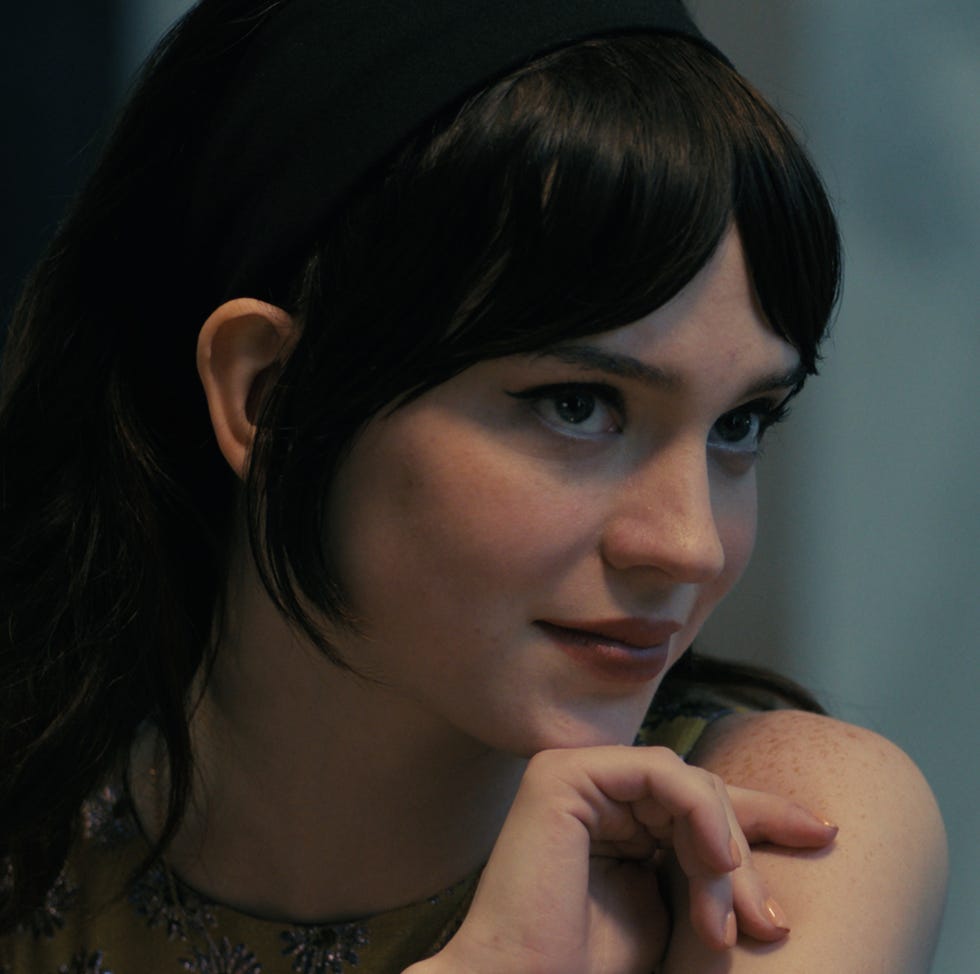 A person with dark wavy hair and a headband seated possibly in a contemplative state A person with dark wavy hair and a headband seated possibly in a contemplative state
