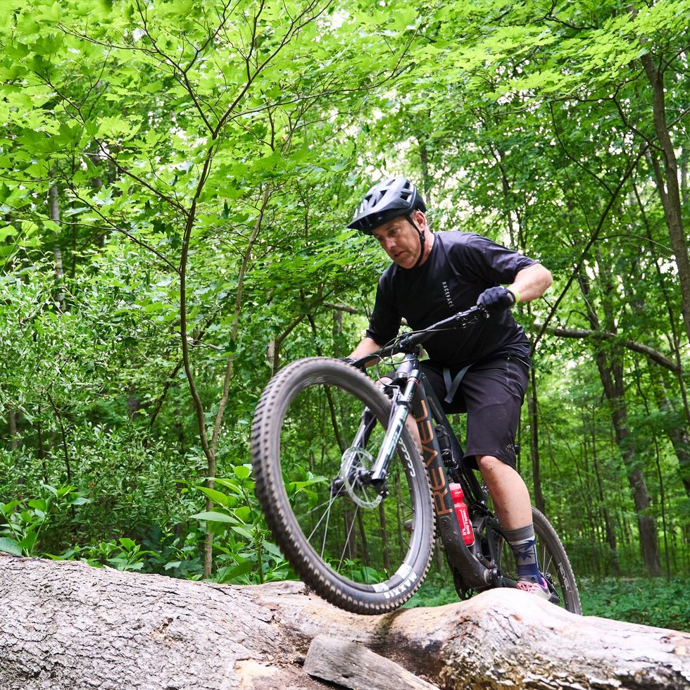 a man riding a bike on a rock in the woods