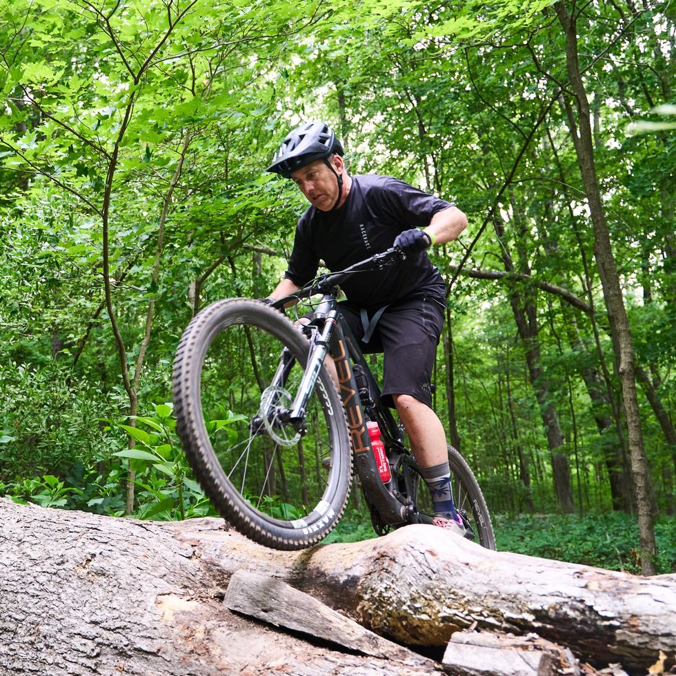 a man riding a bike on a rock in the woods
