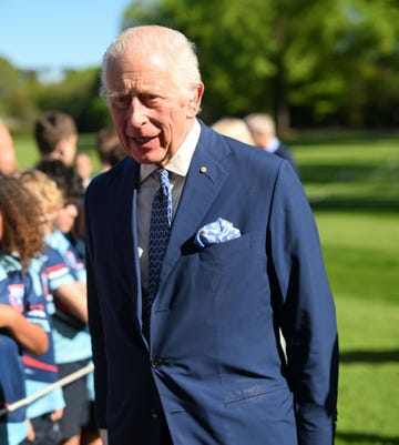 el monarca britanico con una americana azul marino con corbata y panuelo en los mismos tonos