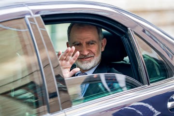 el rey felipe saludando desde la parte de atras de un coche